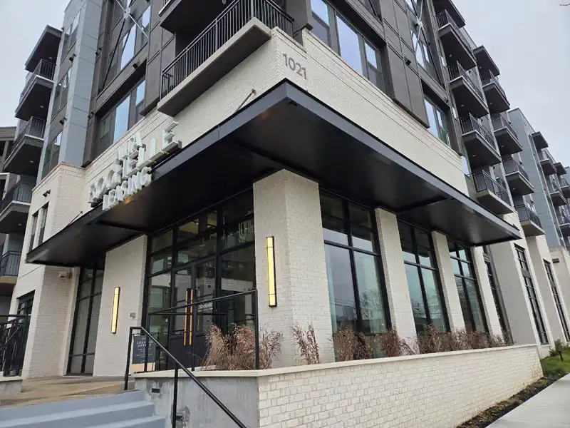 Corner view of a contemporary apartment building with large windows and a covered leasing office entrance.