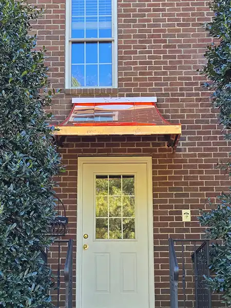 Copper metal door awning installed above door on brick home